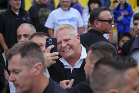 Ontario Premier Doug Ford takes a selfie with a man in the middle of a crowd