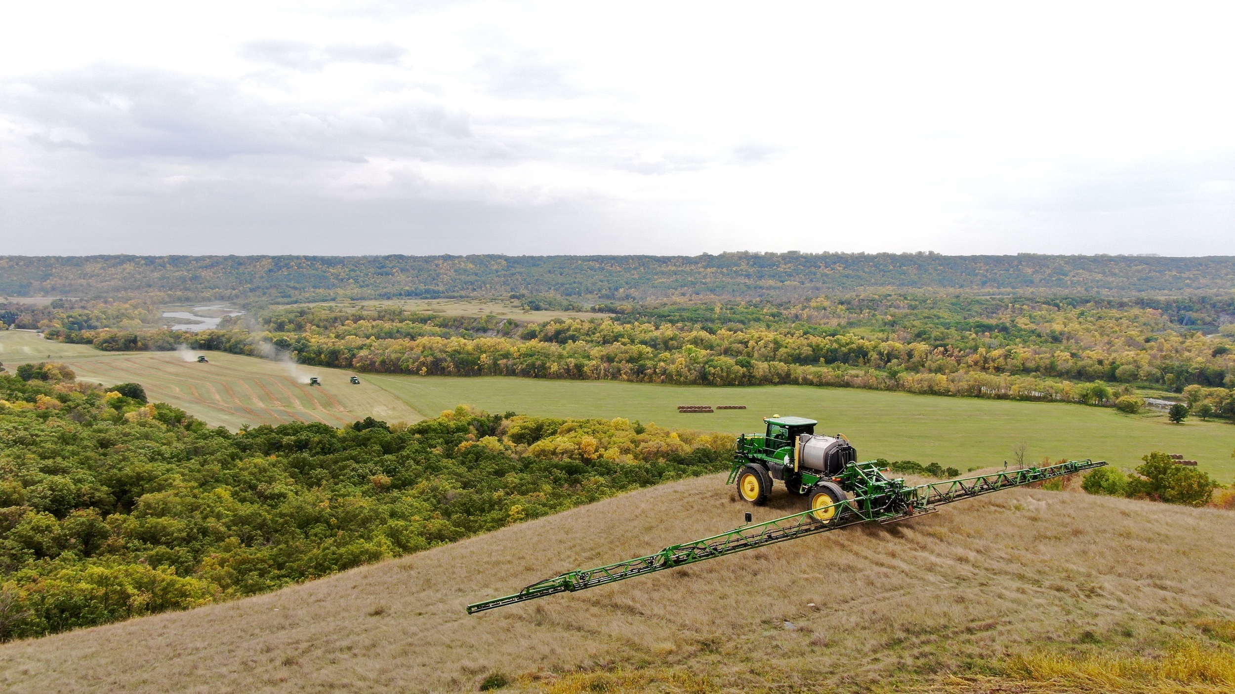 Large farm equipment in a field surrounded by trees