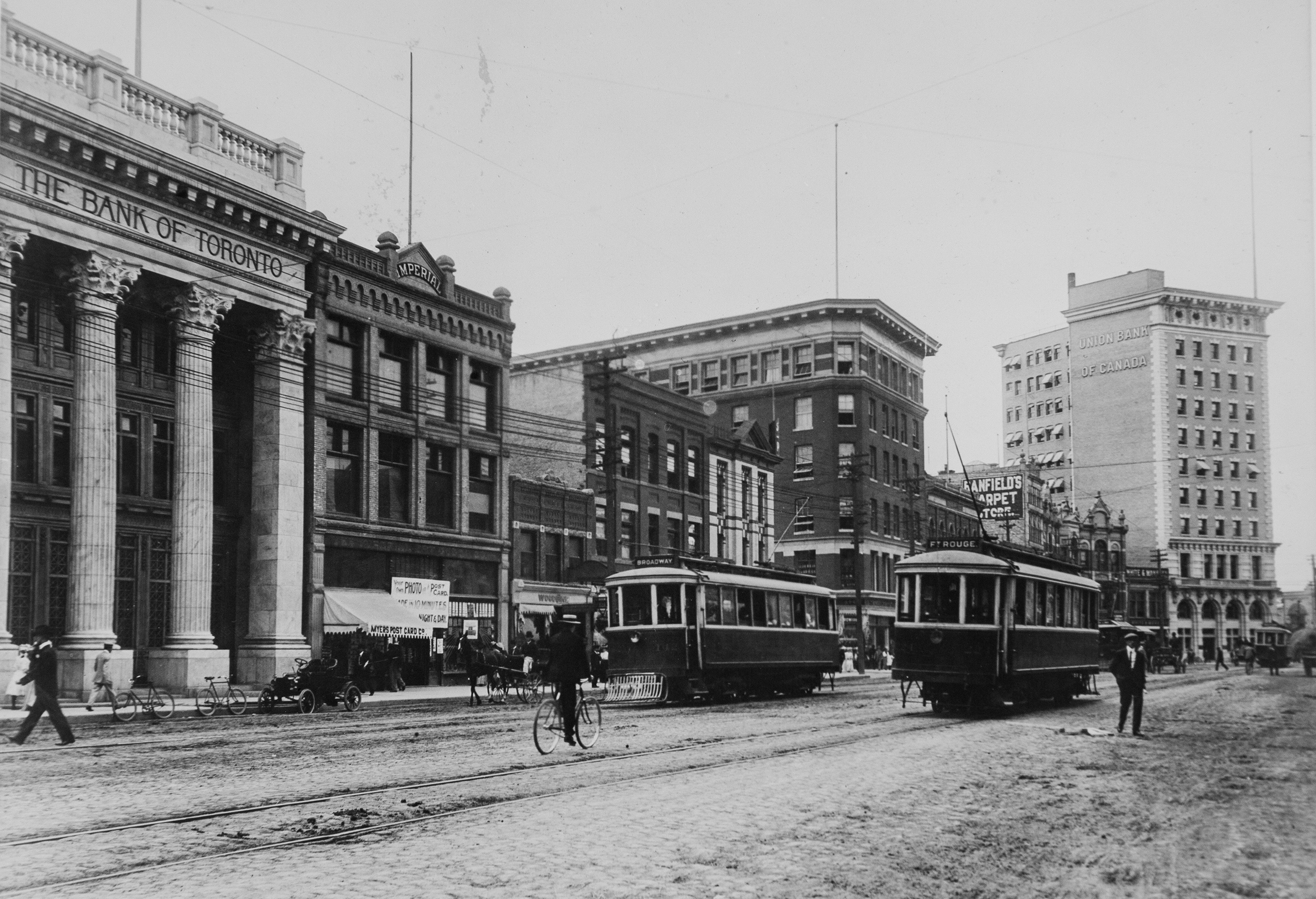 Two street cars drive down Main Street in Winnipeg, sharing the road with cyclists and pedestrians