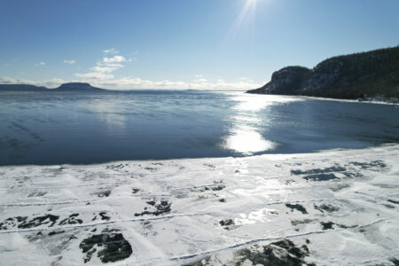Blue sky over open water on Lake Superior, with ice cover in the foreground coming off the shore