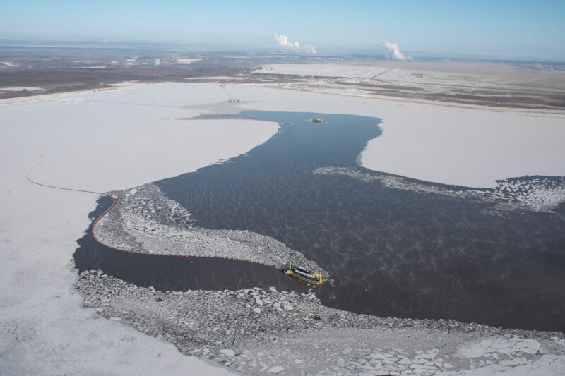 Equipment in the un-frozen liquid of a tailings pond at a Suncor open pit oilsands mine in the middle of winter