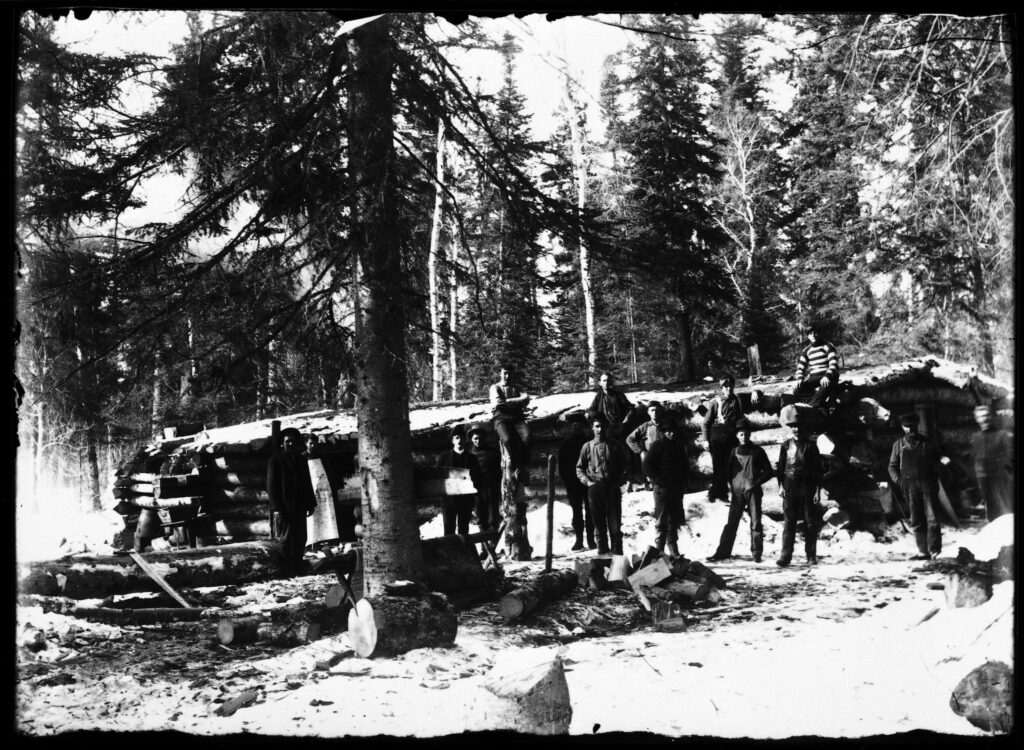 Billy Beal: More than a dozen men stand in front of a cook and bunkhouse built with logs near the Red Deer Lake , Manitoba in 1920