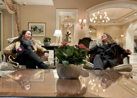 Narwhal co-founder and executive editor Carol Linnitt on the left, co-founder and editor-in-chief Emma Gilchrist on the right, sitting in a hotel lobby, deliriously laughing looking.