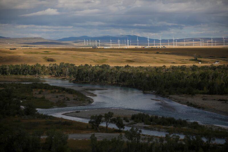 Wind turbines in southern Alberta visible in a landscape with a river, forests and mountains