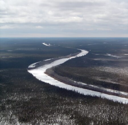 Aerial view of the Albany River with ice on it, flowing through boreal forest