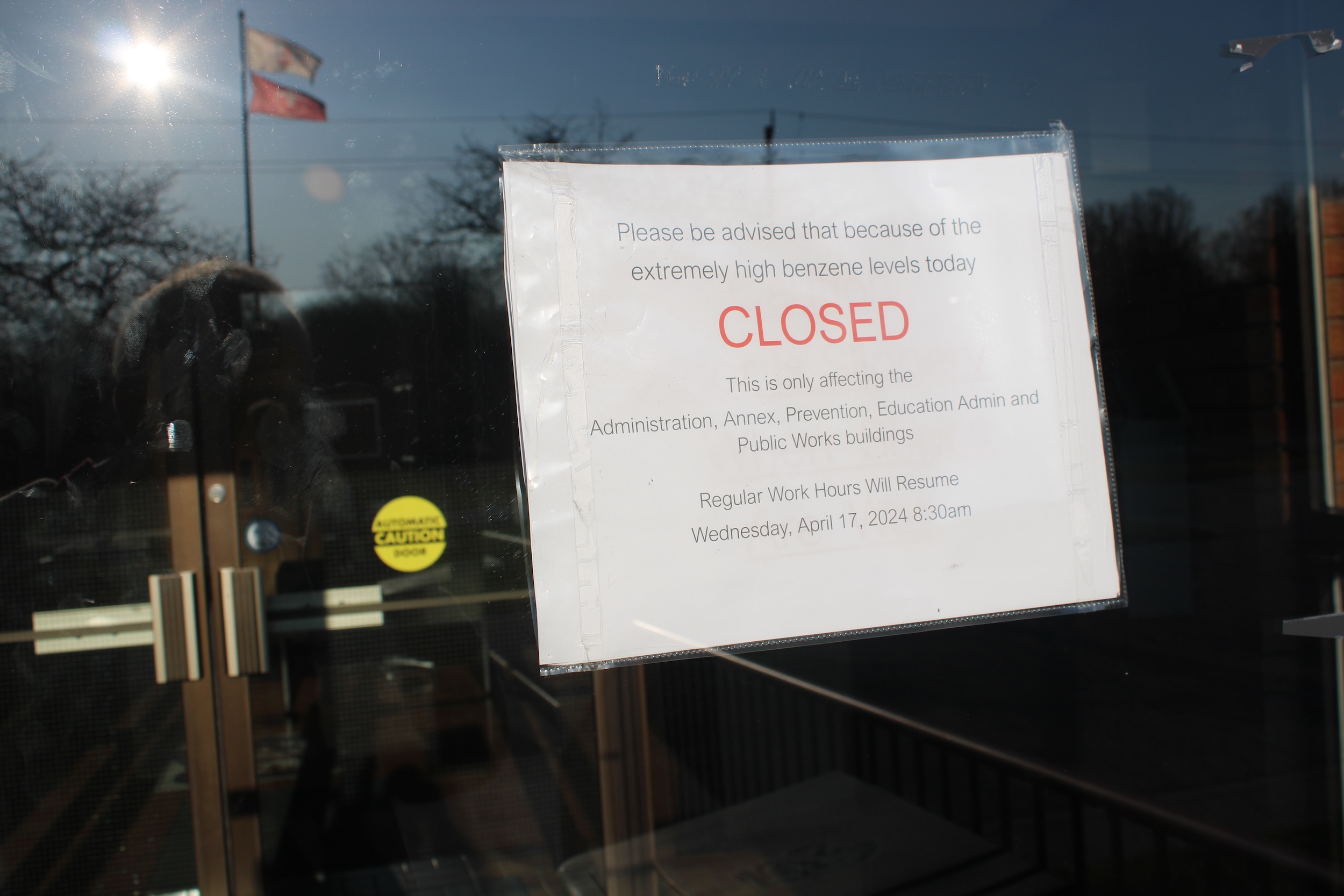 A sign is posted on a glass door. It reads, in part, "Please be advised that because of the extremely high benzene levels today, CLOSED."