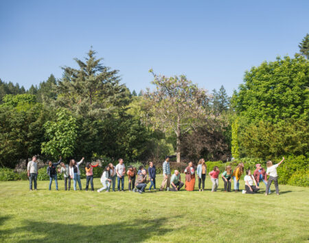 About 20 Narwhal staffers stand in a long line, posing for a group selfie. They are on a green field with trees and blue sky behind.