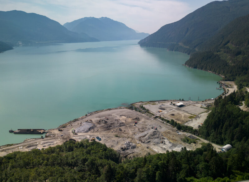 An aerial view of the Woodfibre LNG site looking out over the green-blue water and mountains of Howe Sound