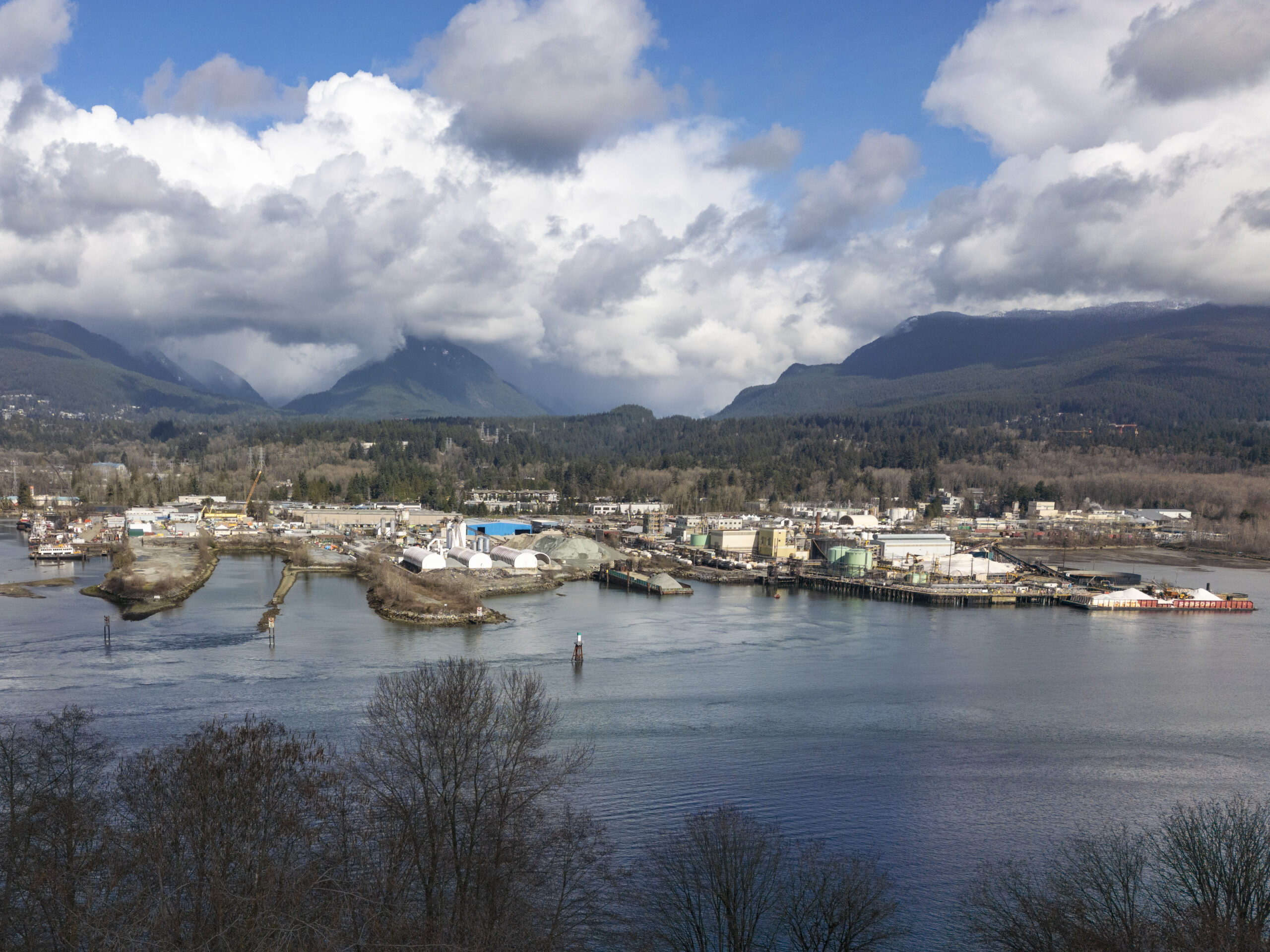 A photo from across the inlet of Chemtrade Electrochem in a commercial-industrial area with the north shore mountains visible in the background