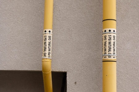 Yellow natural gas pipelines on the side of abuilding