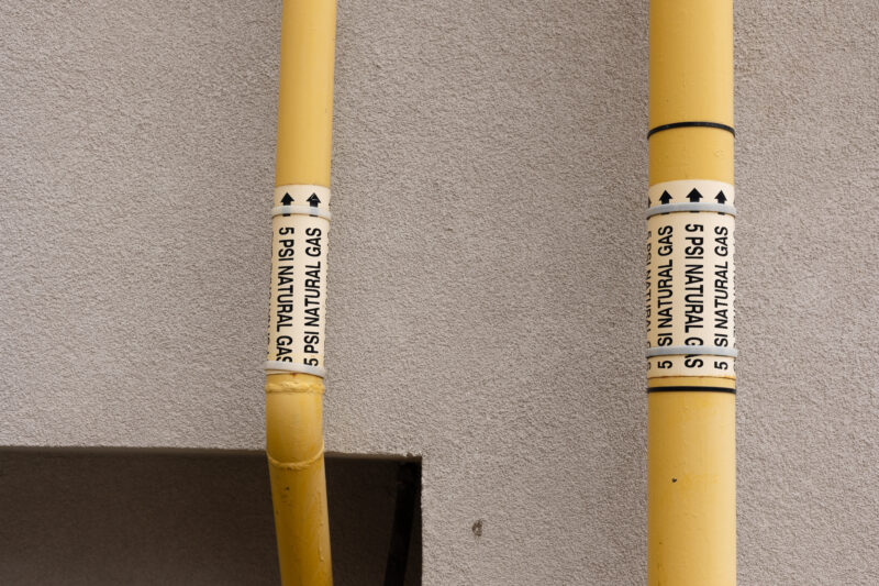 Yellow natural gas pipelines on the side of abuilding