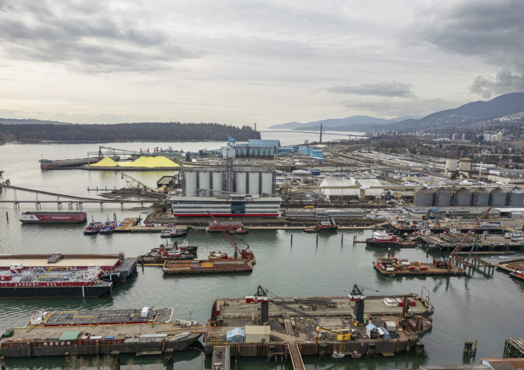 Aerial photo of Seaspan Shipyards in the foreground with Vancouver Whaves, the Lions Gate Bridge and Stanley Park in the background