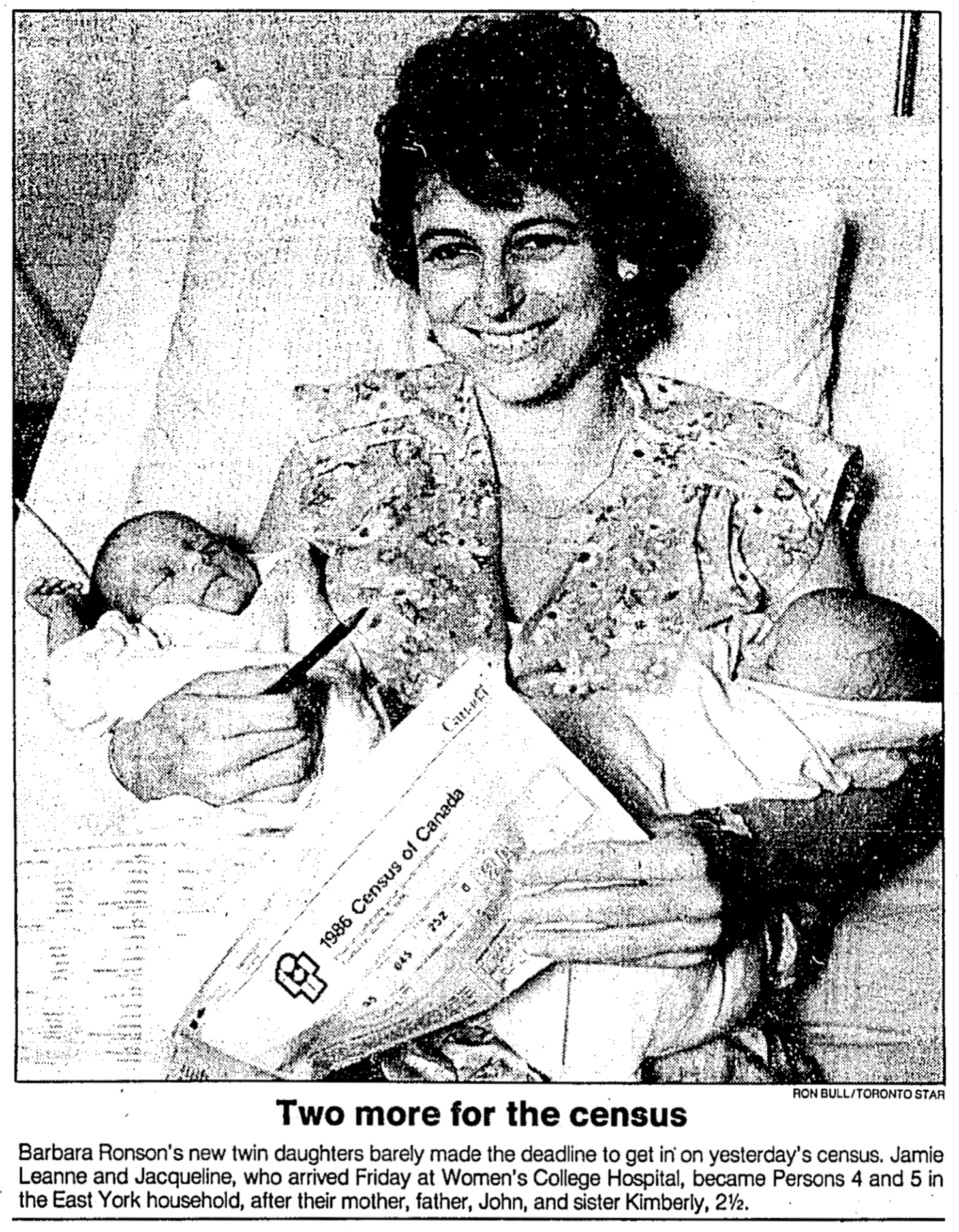 A black and white photo from a newspaper showing a woman holding twin babies with a caption announcing that they were born just in time for the census.
