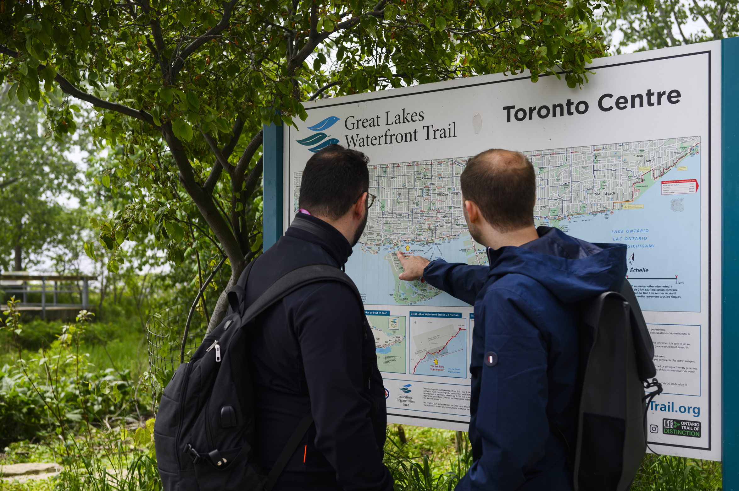 Green* Economy: Two men look at a map of the Great Lakes Waterfront Trail as it passes through Toronto, surrounded by lush greenery