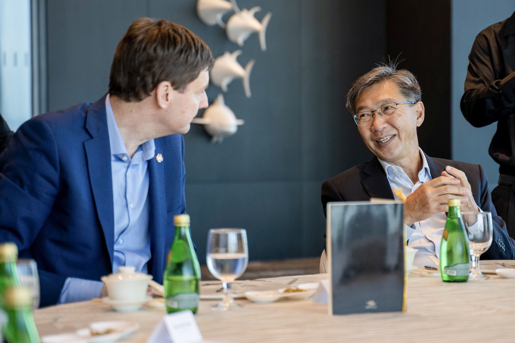 David Eby sits at a formal table, in conversation with an official-looking person.