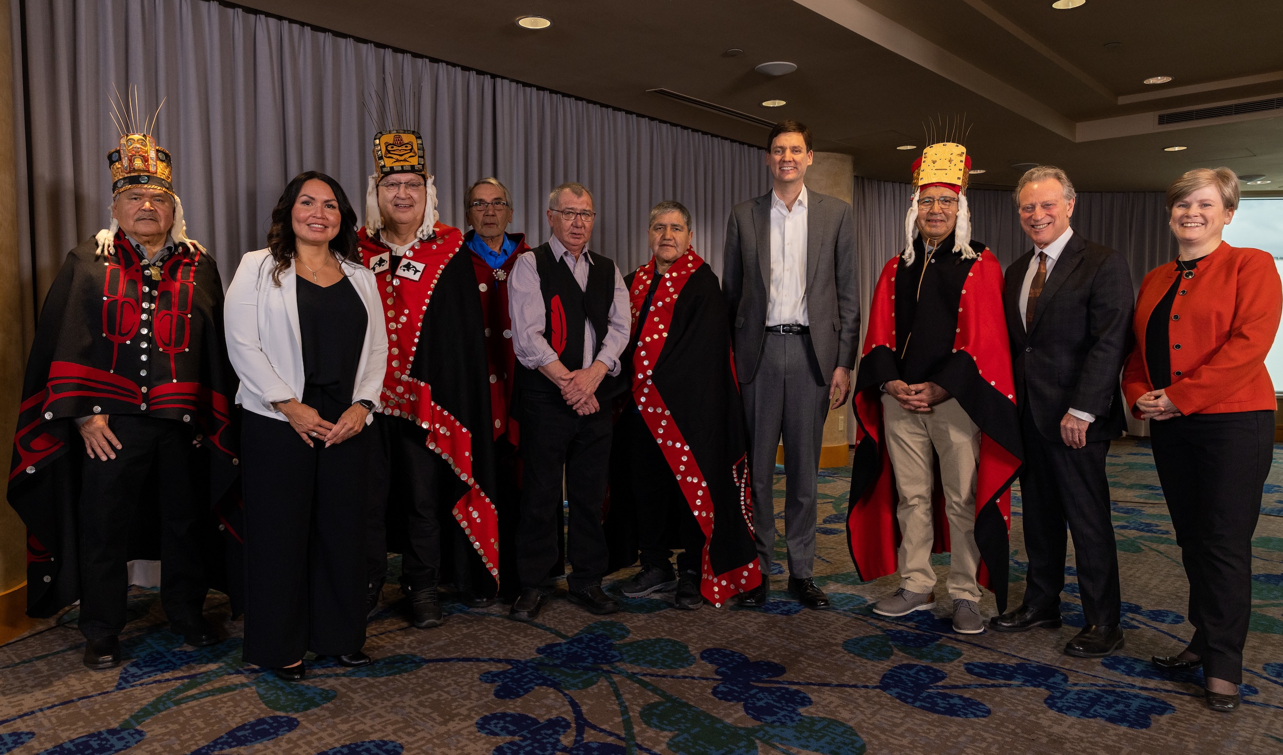 B.C. Premier David Eby poses for a photo with Haisla Chief Crystal Smith and eight other people. Many are dressed in ceremonial Haisla clothing.