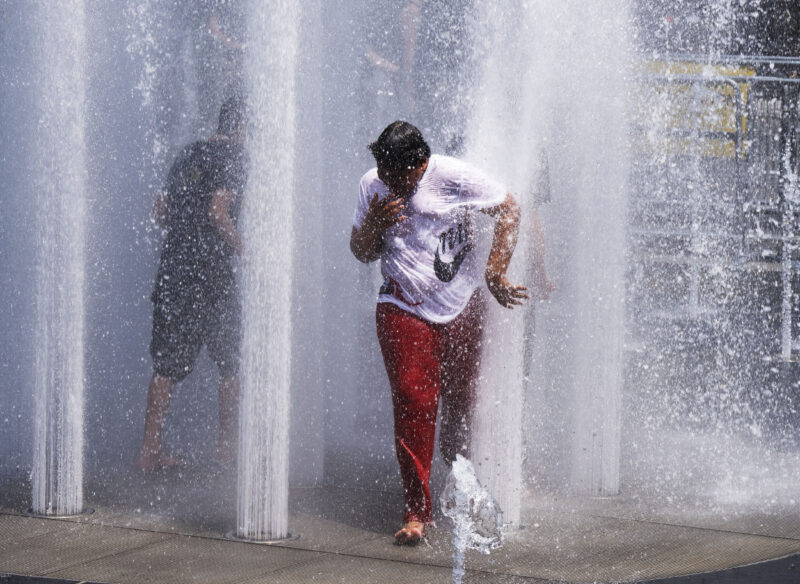 Heat wave: A tween in a t-shirt and pants runs through a fountain in Montreal barefoot, getting doused by water