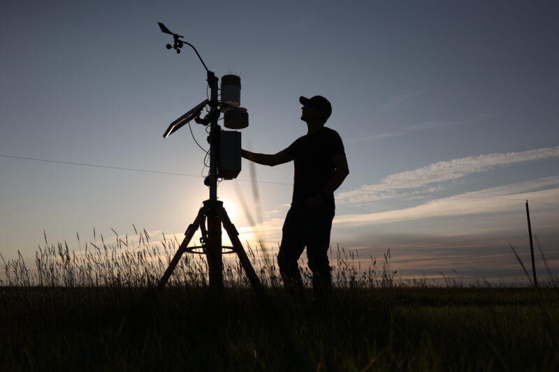 A farmer poses next to a weather and crop management stations near his farm outside Fillmore, Saskatchewan