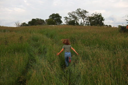 a child runs through a field of tall plants