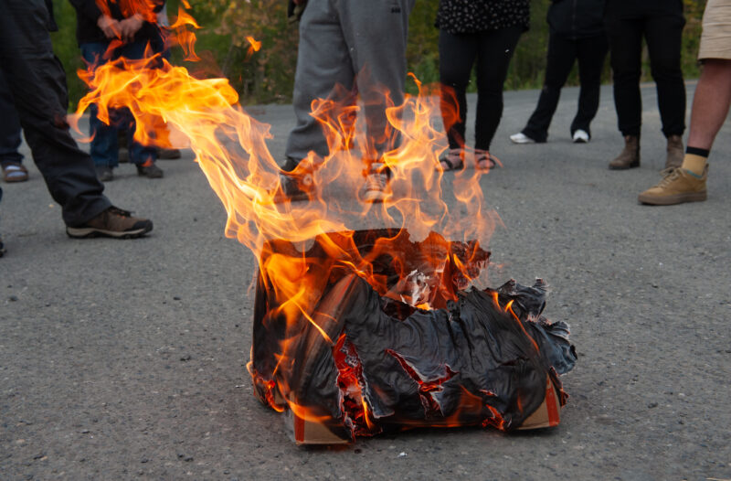 A cardboard box filled with the pages of a Prince Rupert Gas Transmission pipeline benefits agreement burns with the feet of Indigenous leaders and supporters surround it