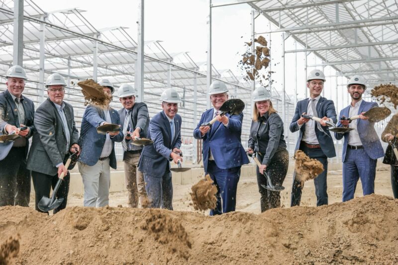 Ontario Premier Doug Ford and members of his cabinet including Energy Minister Stephen Lecce and others dig shovels into a sandy berm and throw sand in the air, wearing white Enbridge hard hats