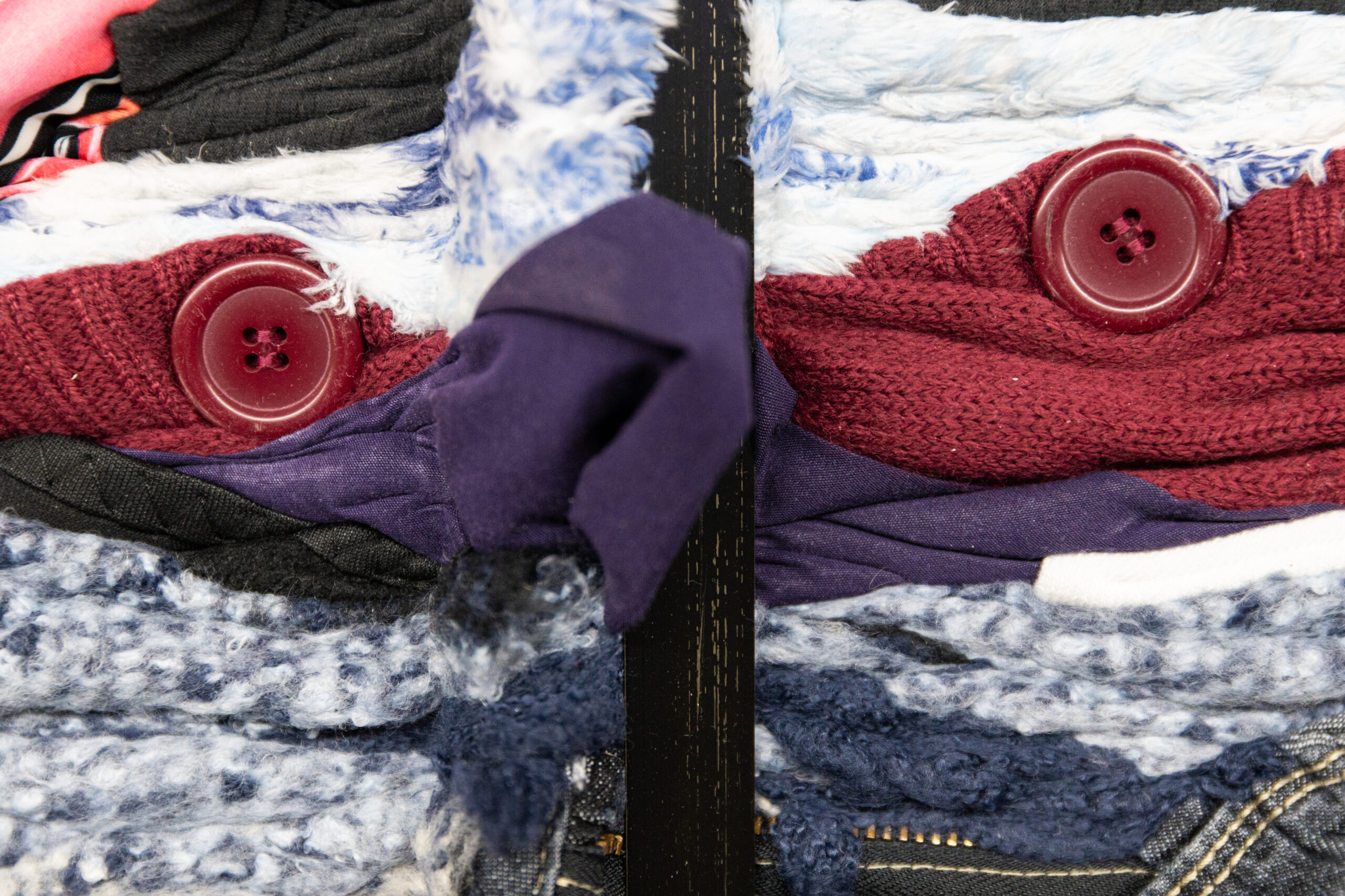 A close up of two red buttons poking out from a compressed clothing bale
