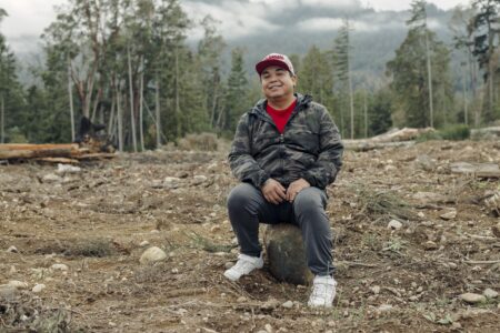 George Harry sits on a rock on recently cleared land — the site of Malahat Nation's battery manufacturing facility.