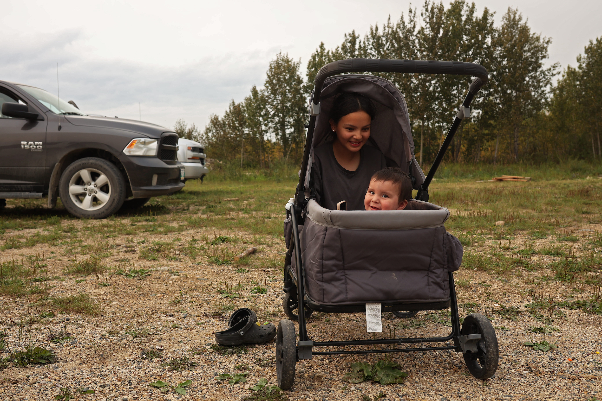 A child and a baby sit in a stroller outdoors