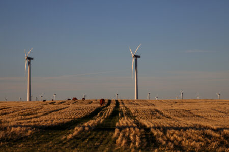 Wind turbines sit in a farm field on the Canadian prairies