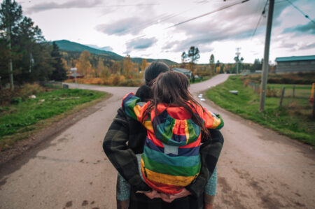 A photo of a woman carrying a child through the Gitxsan village of Kispiox