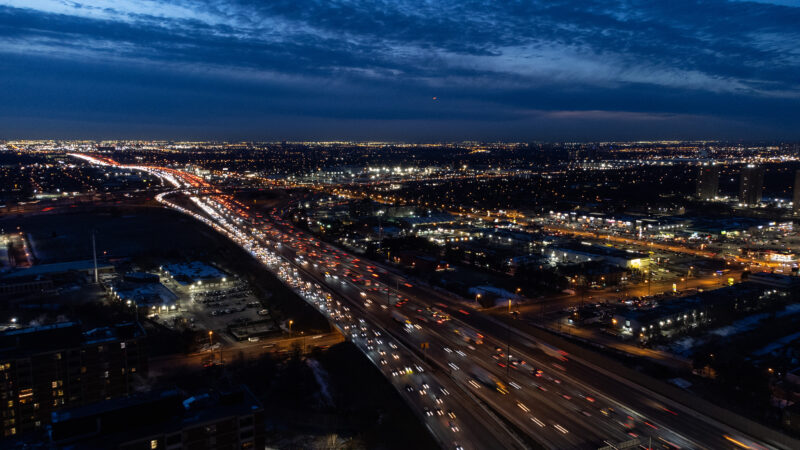 An aerial view of Highway 401 in Toronto, packed with cars whizzing by, seen at night