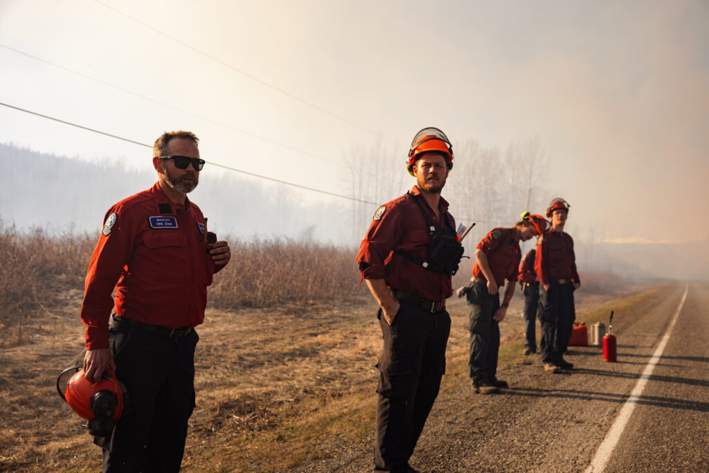 BC Wildfire Service members standing alongside a road with smoky skies