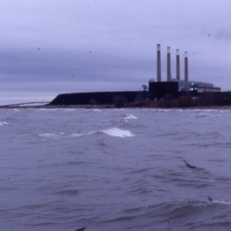 a large body of water with a factory and smoke stacks