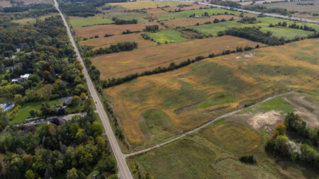 Highway 413: an aerial view of a highway running between a forest and farm fields