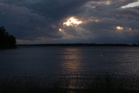 A view of the St. Lawrence River under heavy cloud cover, with the sun peeking out.