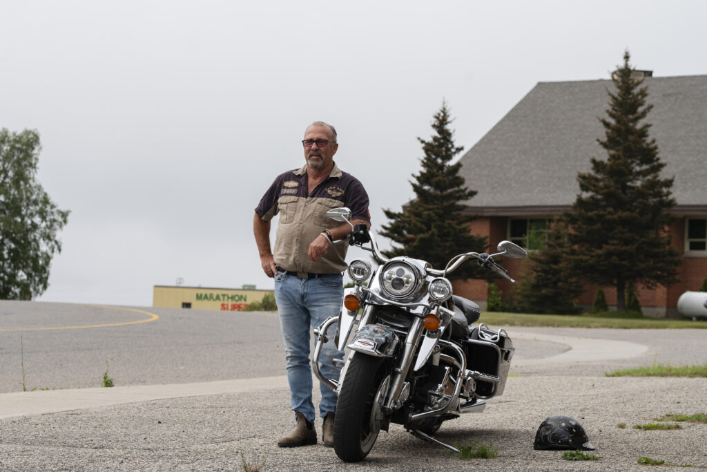 Rick Dumas poses with his motorcycle beside a street in Marathon, Ontario