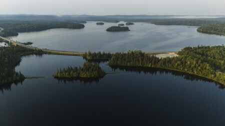 An aerial view of a highway crossing over a lake that's dotted with forested islands