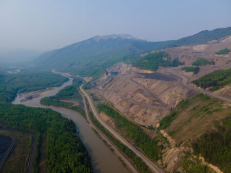 A strip mine in the Alberta Rockies, showing a carved slope abutting a river.