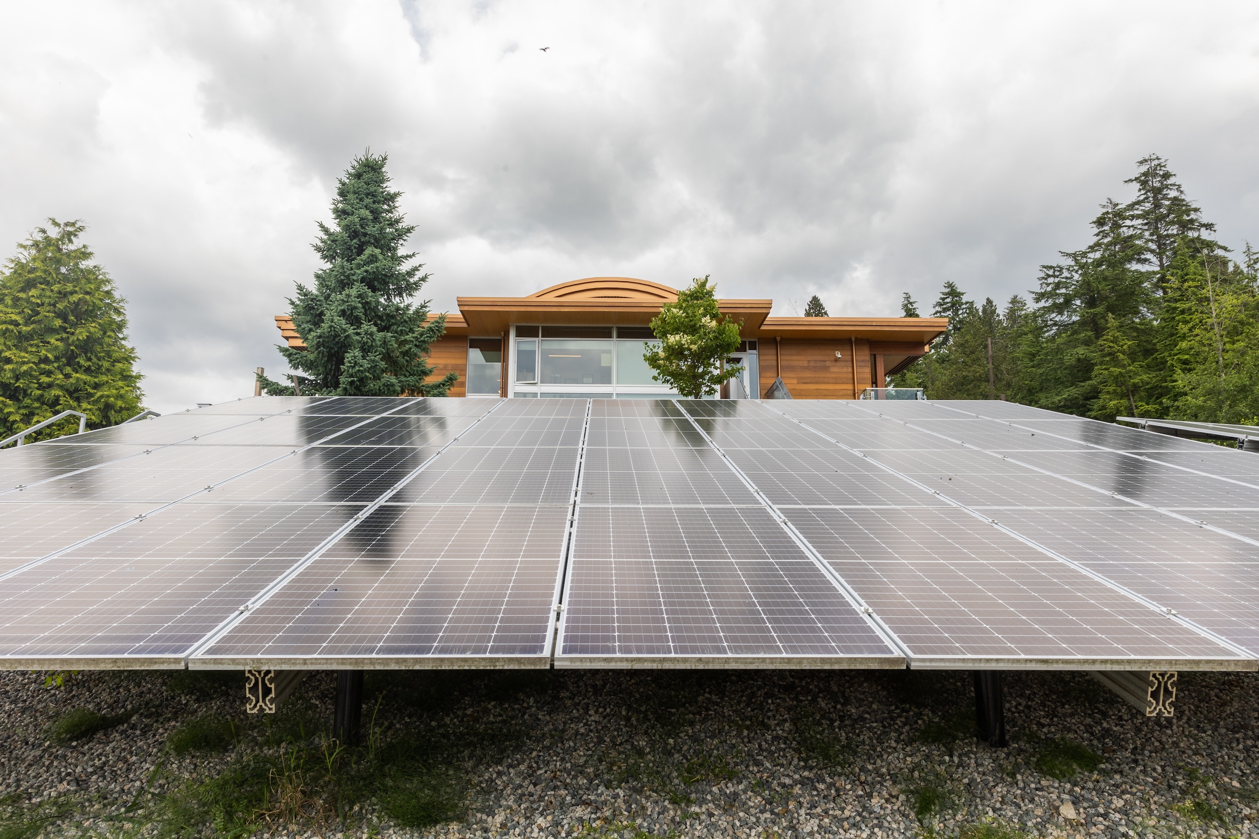 An array of solar panels sits in front of a timber frame building