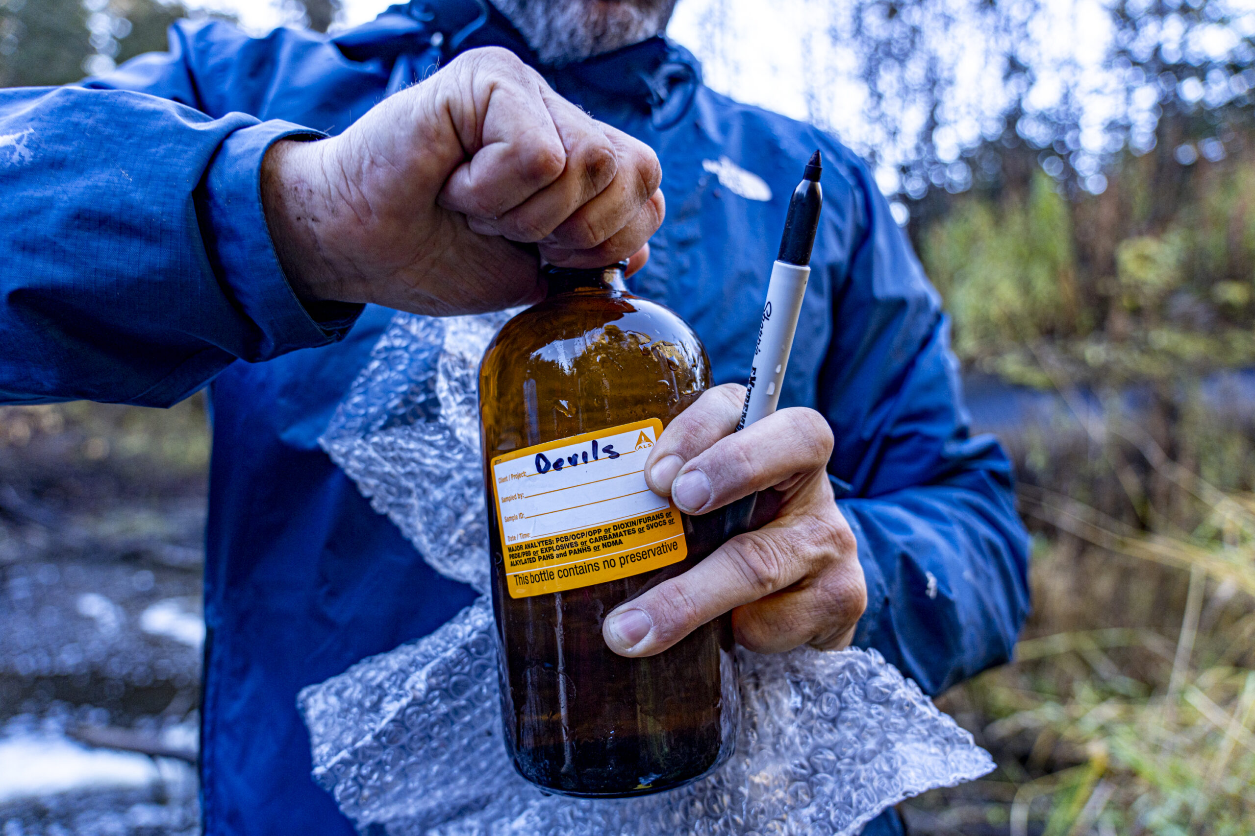 A man in a blue jacket opens a sampling bottle labelled 'Devil's'