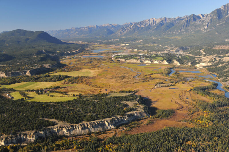 A view of the Columbia River Valley near Radium Hot Spring, B.C. There are mountains to the north and the river cuts between rocky bluffs