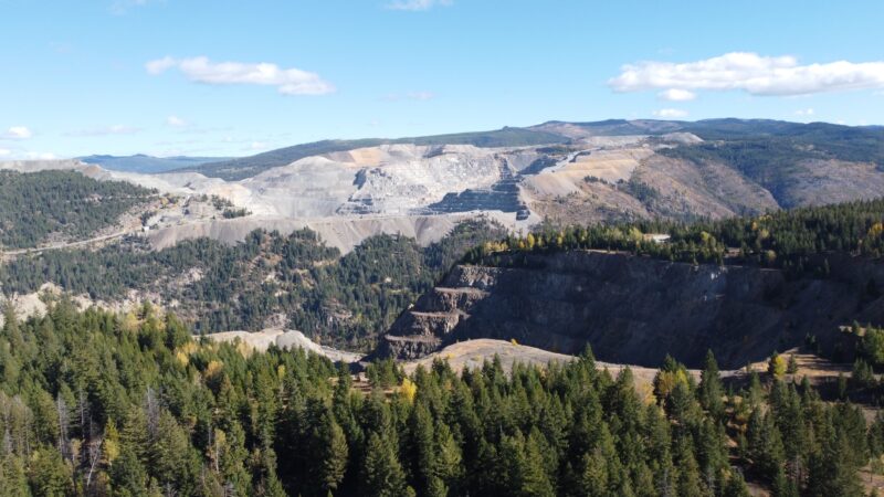 A hillside is cut away into staircase-like tiers at an open pit mine site