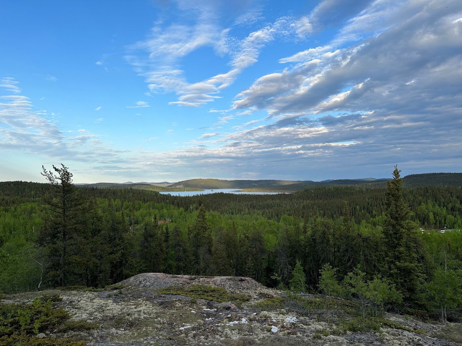 A big sky over coniferous trees and a rocky landscape