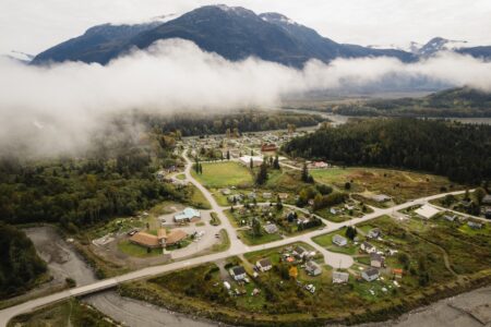 Aerial view over a small rural community with low clouds and mountains beyond