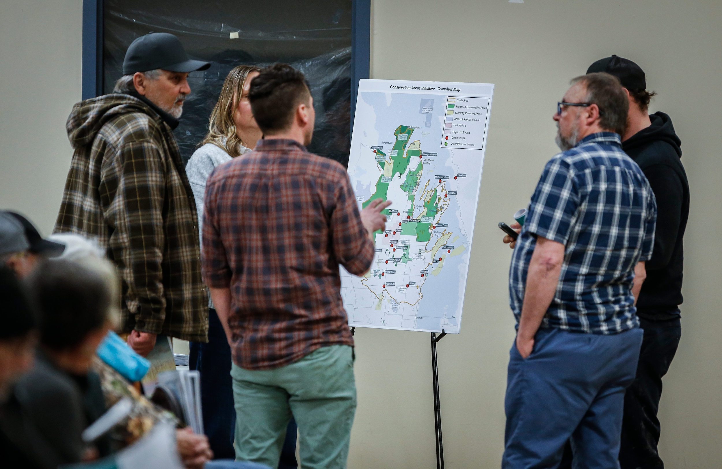 A group of people gather around a map at an nformation session for Indigenous led protected areas