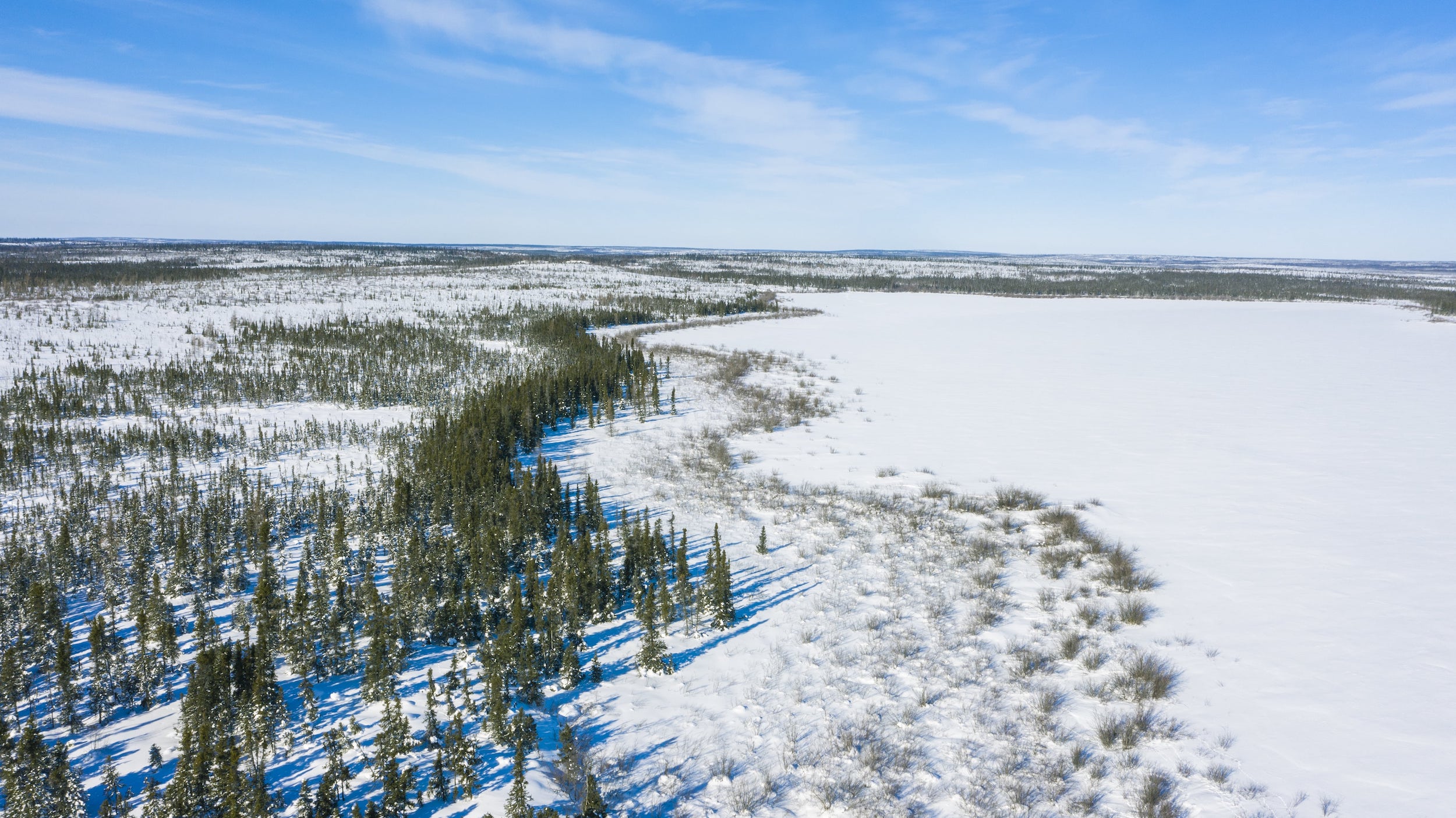 aerial view of a snowy frozen lake under blue skies