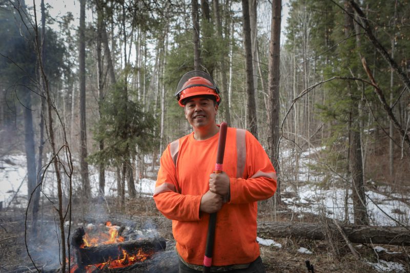 Charles Kruger stands in front of a burning slash pile in syilx territory, where technicians are mitigating the risk of wildfire.