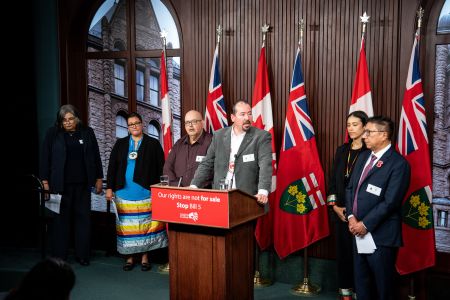 Five First Nations leaders stand at a podium with the sign "Our rights are not for sale Stop Bill 5"
