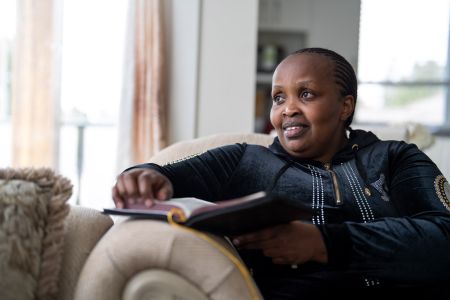 Margaret Wanyoike sits on a couch in her energy-efficient apartment in New Westminster, B.C.