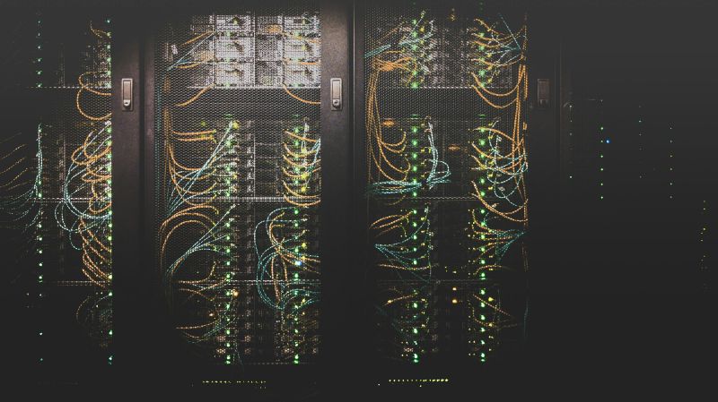 Colourful wires plugged into machines behind translucent doors in a data centre